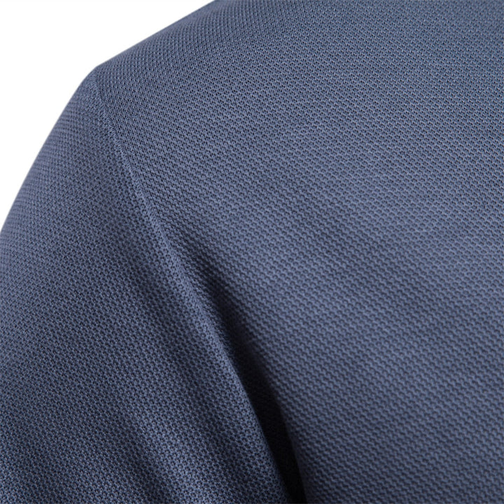 Détail de la texture du tissu du polo bleu, mettant en évidence sa finition soignée et sa matière douce, idéale pour une allure élégante et un confort optimal.