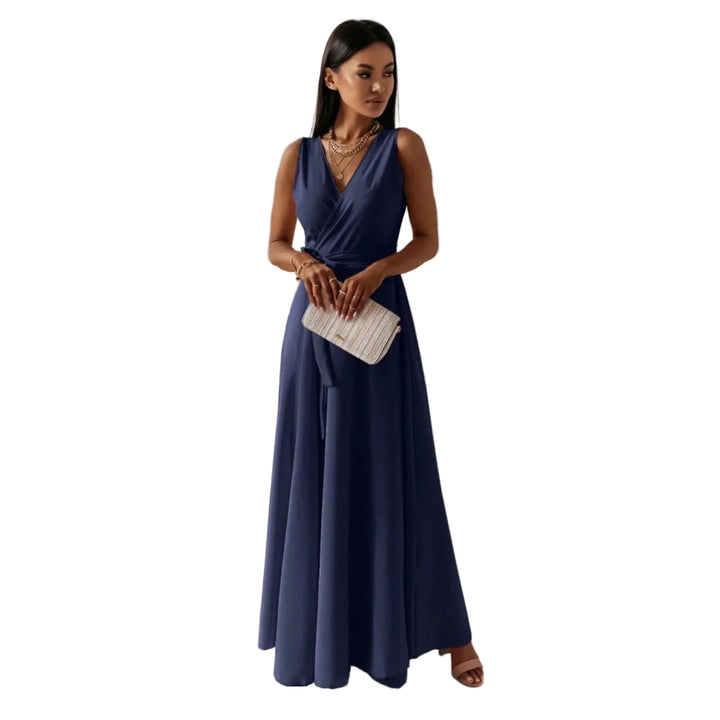 Bleu marine, décolleté en V croisé, taille marquée et jupe fluide, avec sandales et pochette, dans un intérieur lumineux.