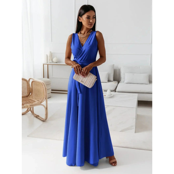 Bleu roi, décolleté en V croisé, taille ceinturée et jupe fluide, avec sandales et pochette, dans un salon lumineux.