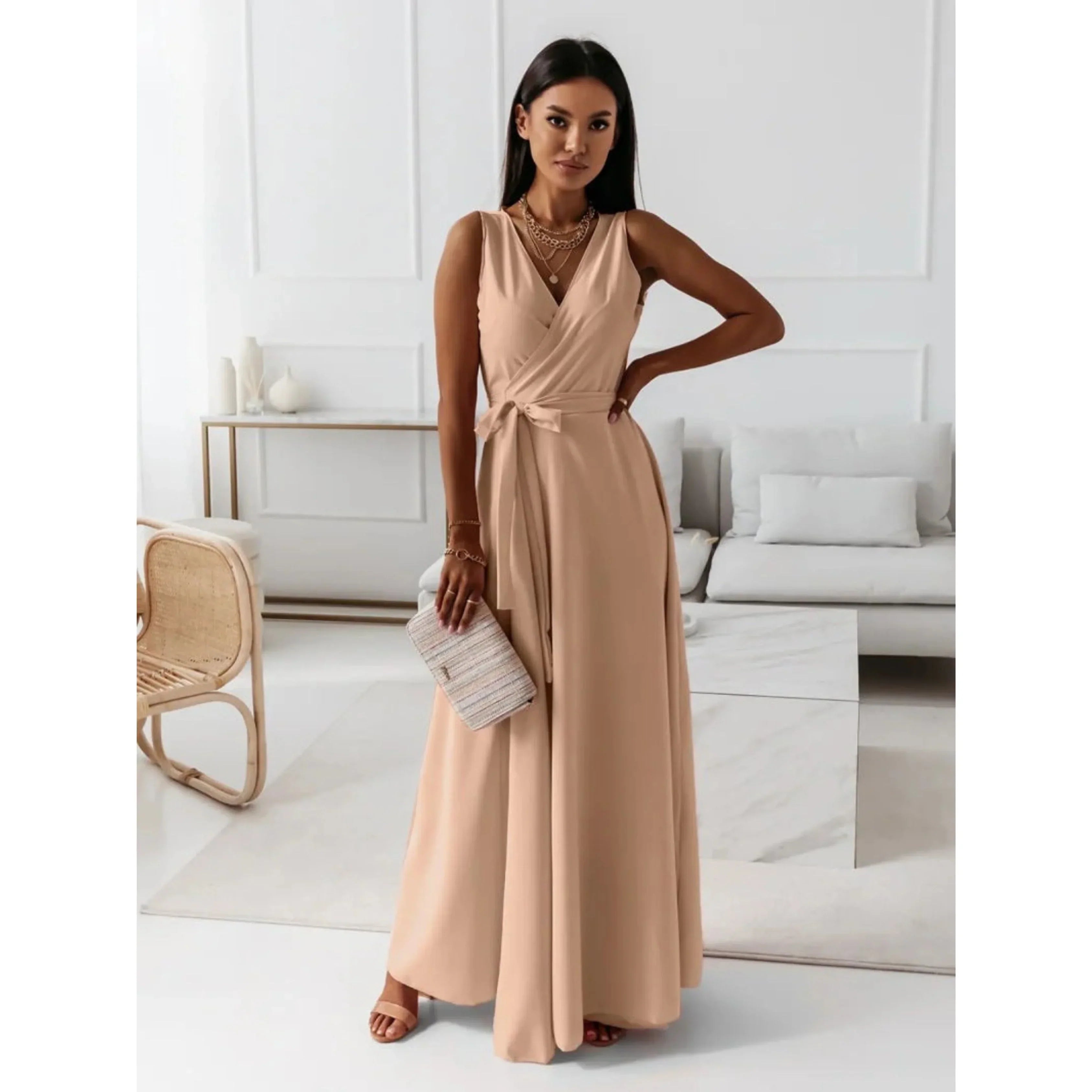 Beige nude, décolleté en V croisé, taille ceinturée avec nœud et jupe fluide, avec sandales et pochette, dans un intérieur lumineux.