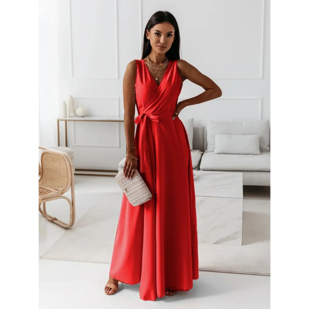 Rouge, décolleté en V croisé, taille ceinturée avec nœud et jupe fluide, avec sandales et pochette, dans un salon lumineux.