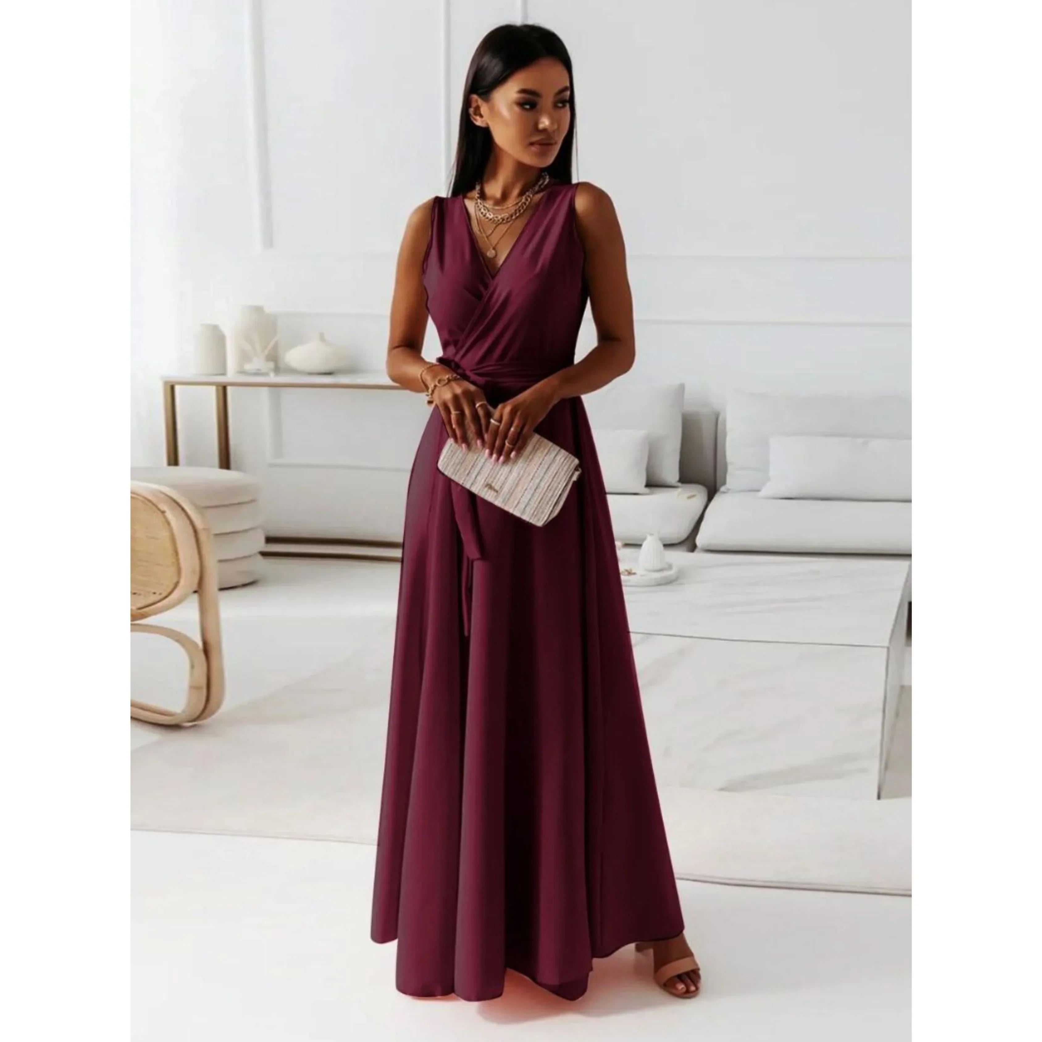 Bordeaux, décolleté en V croisé, taille ceinturée et jupe fluide, avec sandales et pochette, dans un salon lumineux.