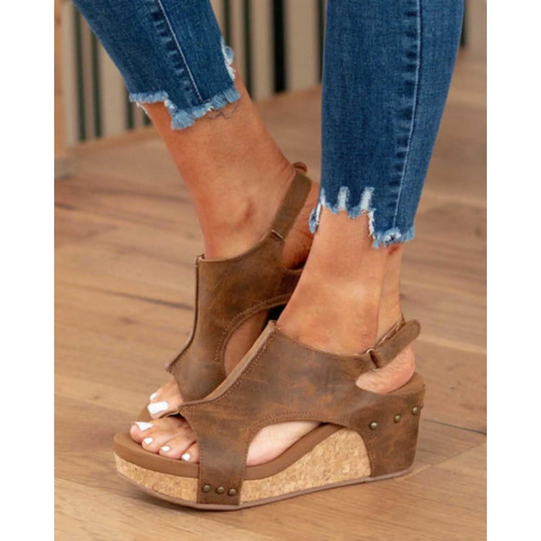 Sandales en cuir pour femmes Elodine, avec une plateforme en liège et des détails en métal, portées avec un jean déchiré.