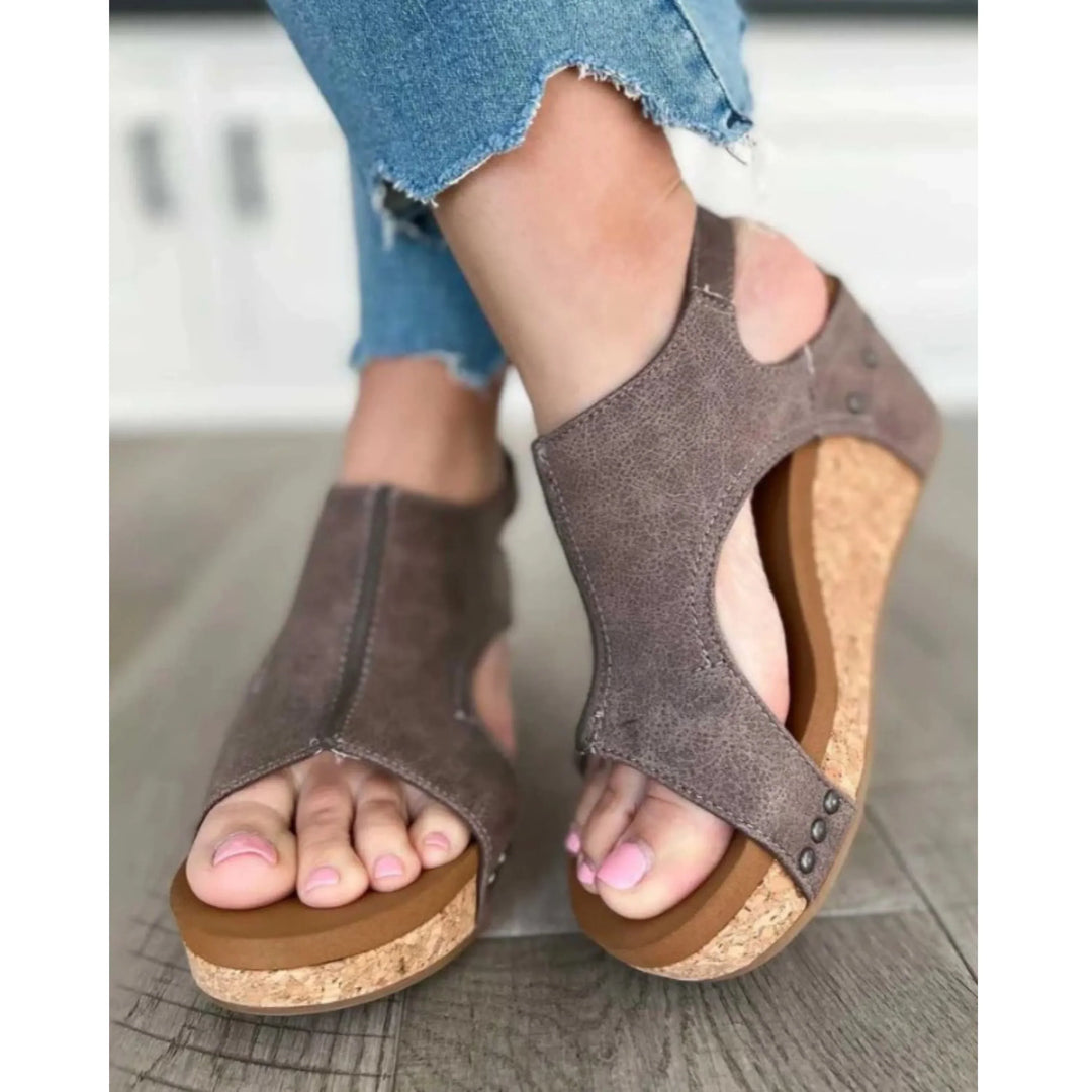 Sandales en cuir marron Elodine pour femmes avec plateforme en liège, détails cloutés et design ouvert, portées avec un jean déchiré.