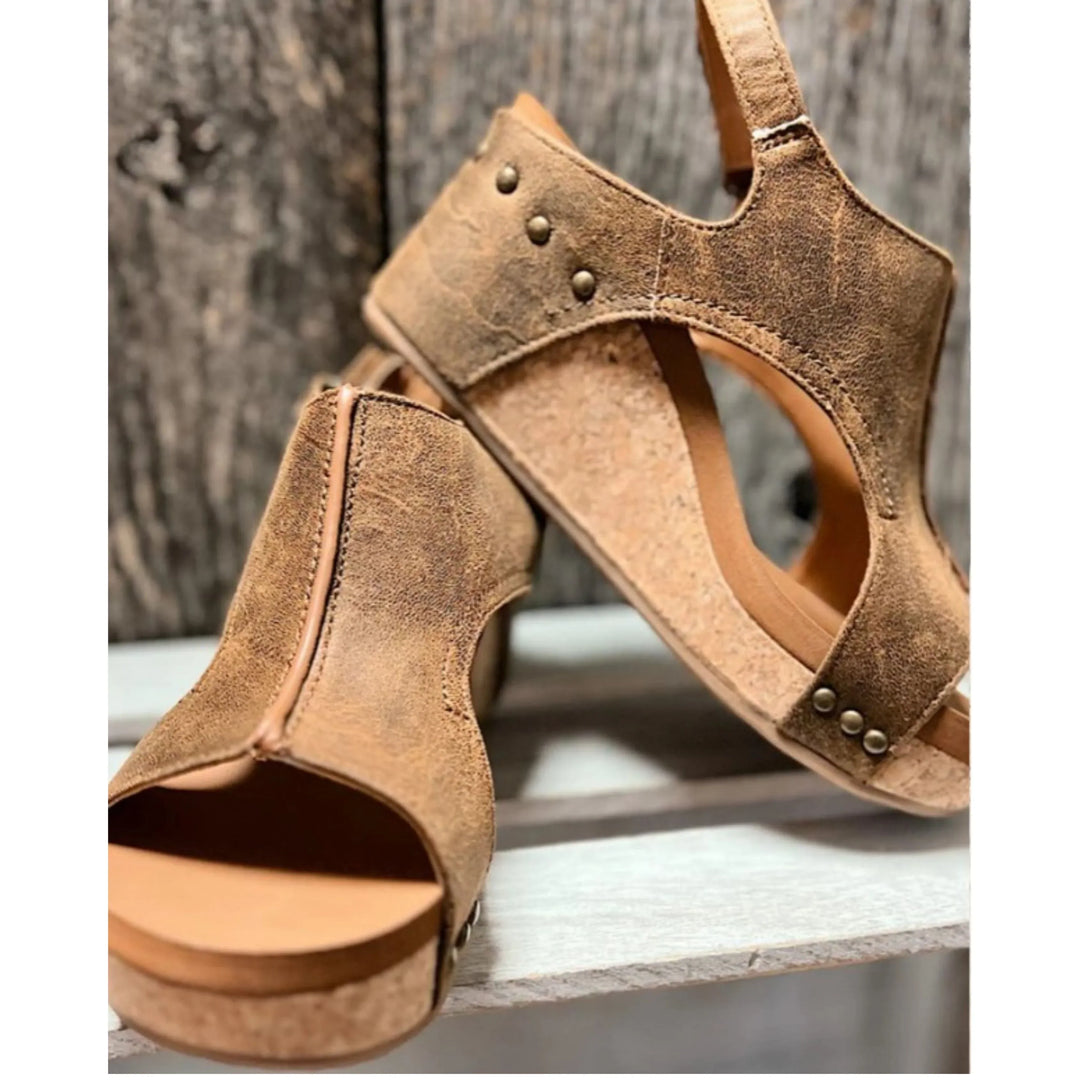 Sandales en cuir marron Elodine pour femmes avec plateforme en liège, détails cloutés et design ouvert, portées avec un jean déchiré.