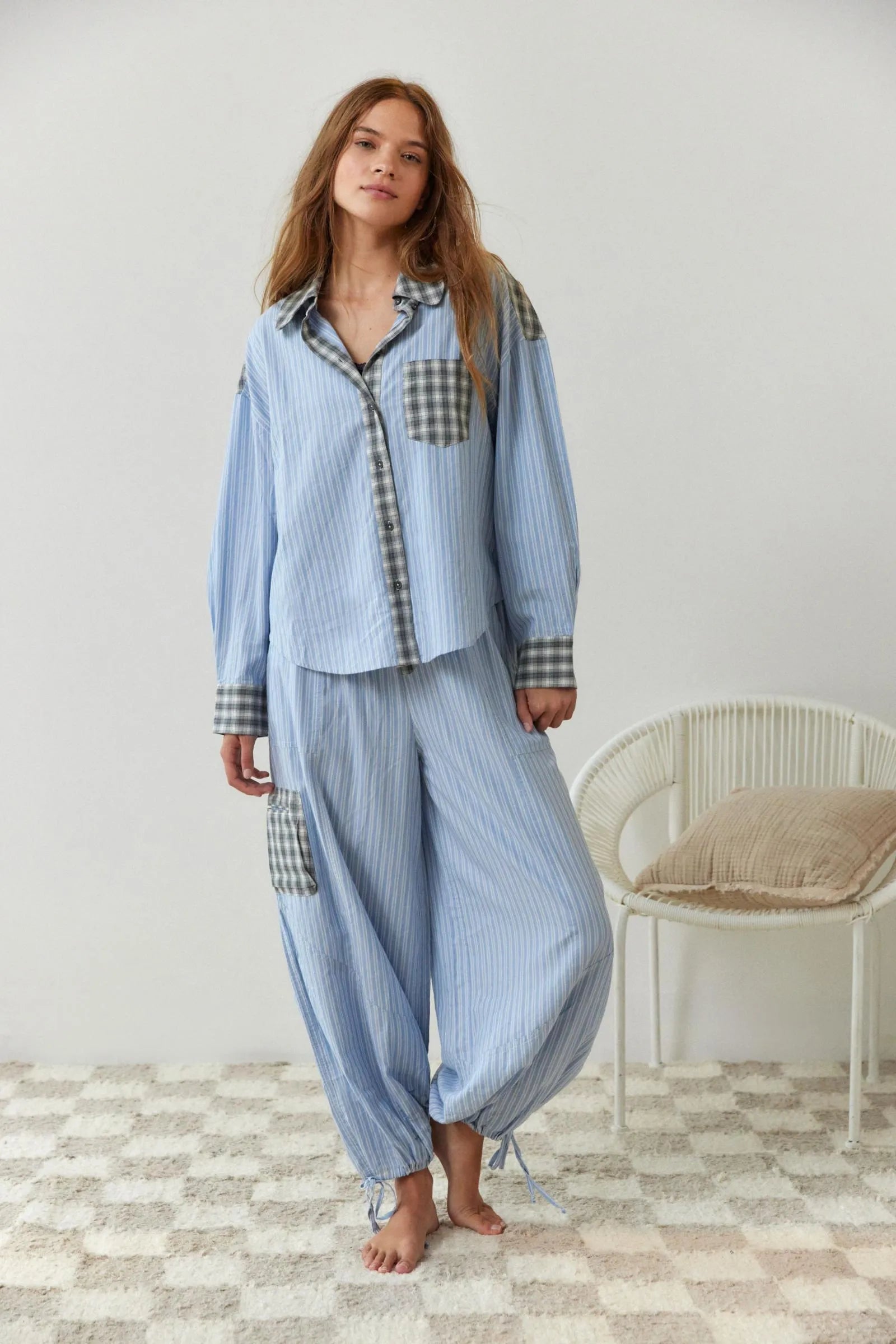 Pyjama pour femme en tissu bleu clair à fines rayures, composé d’une chemise ample ornée d’empiècements à carreaux gris et d’un pantalon large assorti avec poche contrastée. Ensemble doux, léger et confortable, idéal pour des nuits paisibles et la détente.