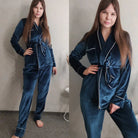 Femme portant un pyjama en velours bleu composé d’une veste croisée à ceinture et d’un pantalon assorti. Ensemble chaud, doux et très confortable, idéal pour l’hiver et les moments cocooning à la maison.