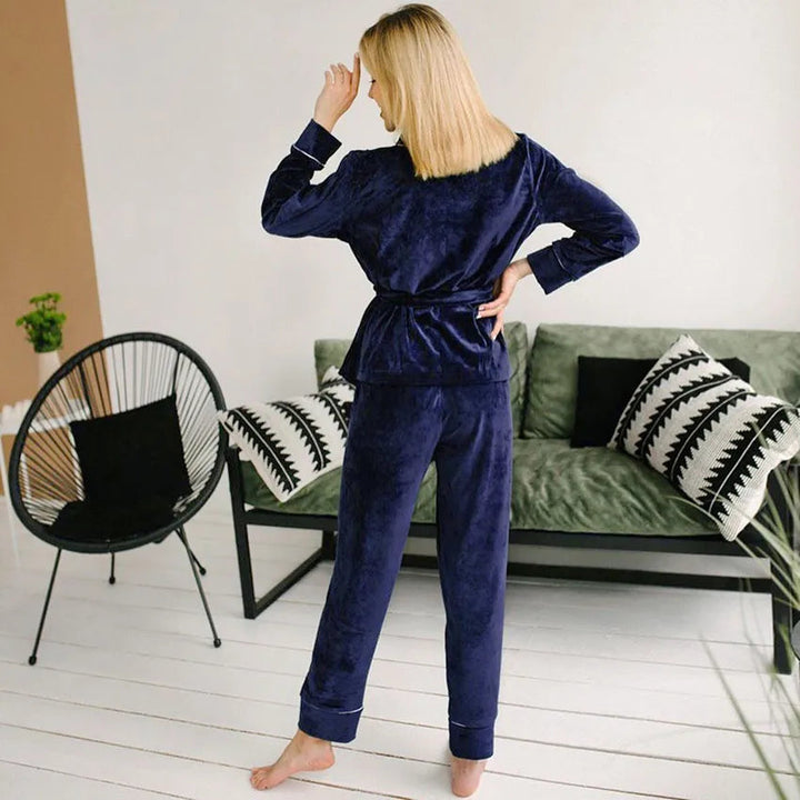 Femme vue de dos portant un pyjama en velours bleu marine composé d’une veste à ceinture et d’un pantalon assorti. Ensemble chaud, doux et très confortable, idéal pour l’hiver et la détente à la maison.