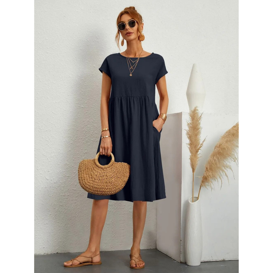 Élégante et confortable. Cette robe bleue marine à manches courtes, avec une coupe évasée et des poches latérales, est parfaite pour un look estival décontracté. Accessoirisée avec un sac en osier, elle allie confort et style pour une journée chic et décontractée.