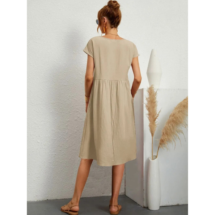 Élégante et confortable. Vue arrière de la robe beige à manches courtes, avec une coupe évasée et une taille froncée, offrant un look décontracté et élégant. Parfaite pour les journées d&