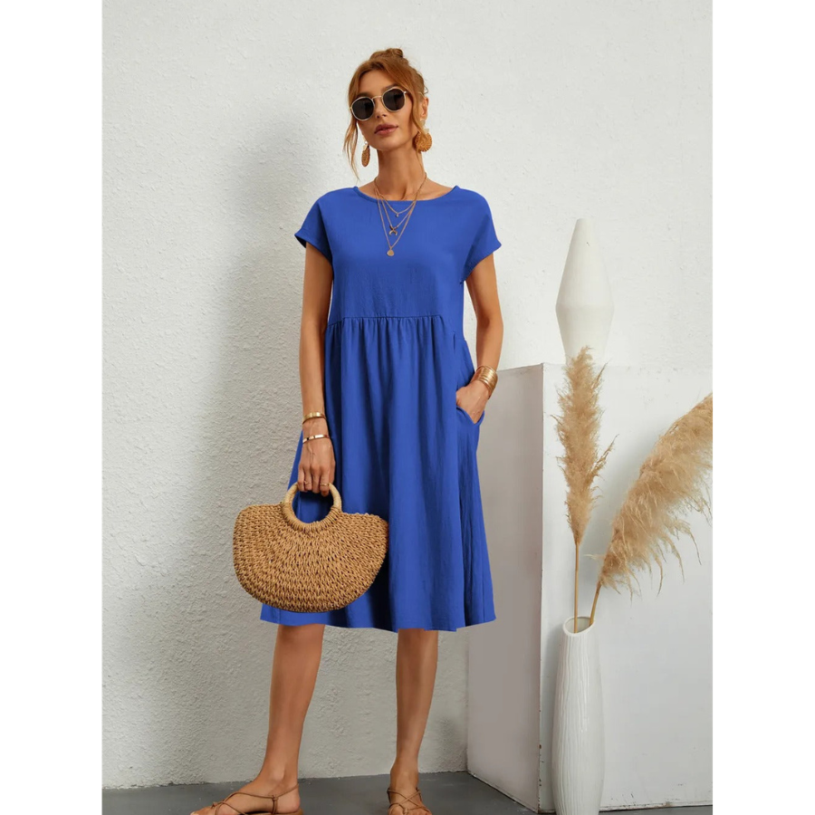 Élégante et confortable. Cette robe bleue à manches courtes, avec une coupe évasée et des poches latérales, combine confort et style. Accessoirisée avec un sac en osier, elle est idéale pour une journée estivale décontractée et élégante.