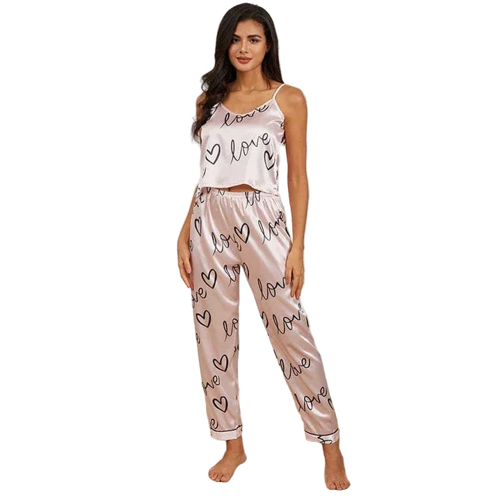 Femme portant le pyjama léger et élégant pour femme, un ensemble en satin rose composé d'un débardeur à fines bretelles et d'un pantalon imprimé de cœurs et du mot, offrant confort et style pour la nuit.
