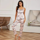 Femme portant le pyjama léger et élégant pour femme, un ensemble en satin rose composé d'un débardeur fluide à fines bretelles et d'un pantalon confortable imprimé de cœurs et du mot, idéal pour des nuits légères et élégantes.