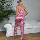 Un ensemble en satin rose composé d'un débardeur à fines bretelles et d'un pantalon fluide orné de cœurs et du mot  offrant un look doux, moderne et confortable pour la soirée.