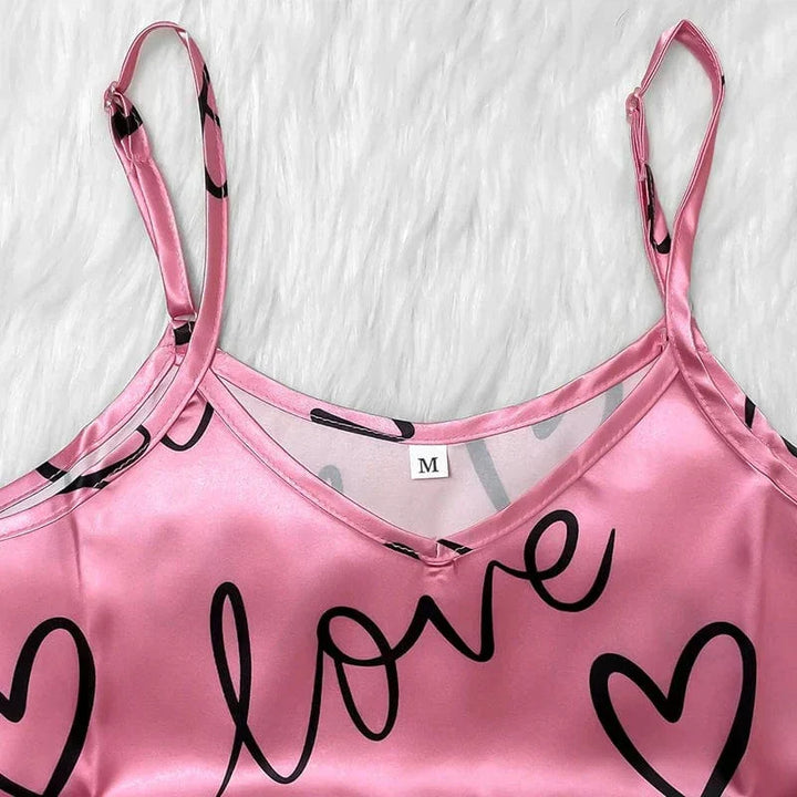 Un débardeur rose en satin à fines bretelles réglables, orné de cœurs et du mot « offert », pour une touche douce et féminine.