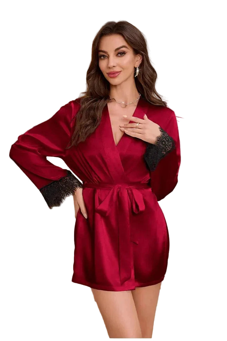 Kimono satin femme Évangéline couleur bordeaux, coupe courte avec ceinture à nouer, manches longues ornées de dentelle noire, porté par un modèle debout dans un intérieur élégant, vue de face.