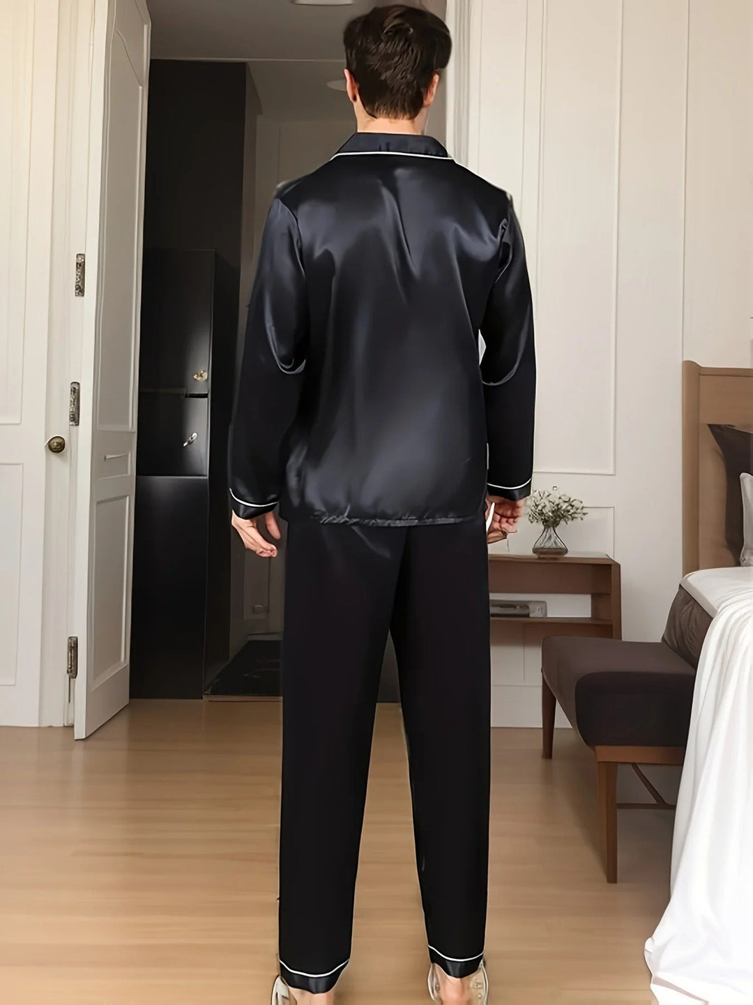 Vue de dos d’un homme portant un pyjama long en satin noir, composé d’une chemise à manches longues avec col à passepoils blancs et d’un pantalon assorti. Ensemble élégant, fluide et confortable, parfait pour la nuit ou les moments de détente à la maison.