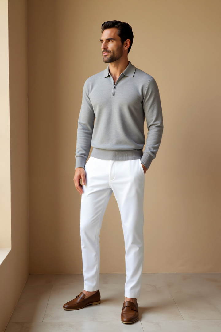 Homme portant un polo zip gris clair avec un col classique, assorti à un pantalon blanc élégant. Ce look moderne et raffiné allie confort et style, parfait pour une tenue quotidienne chic et décontractée.