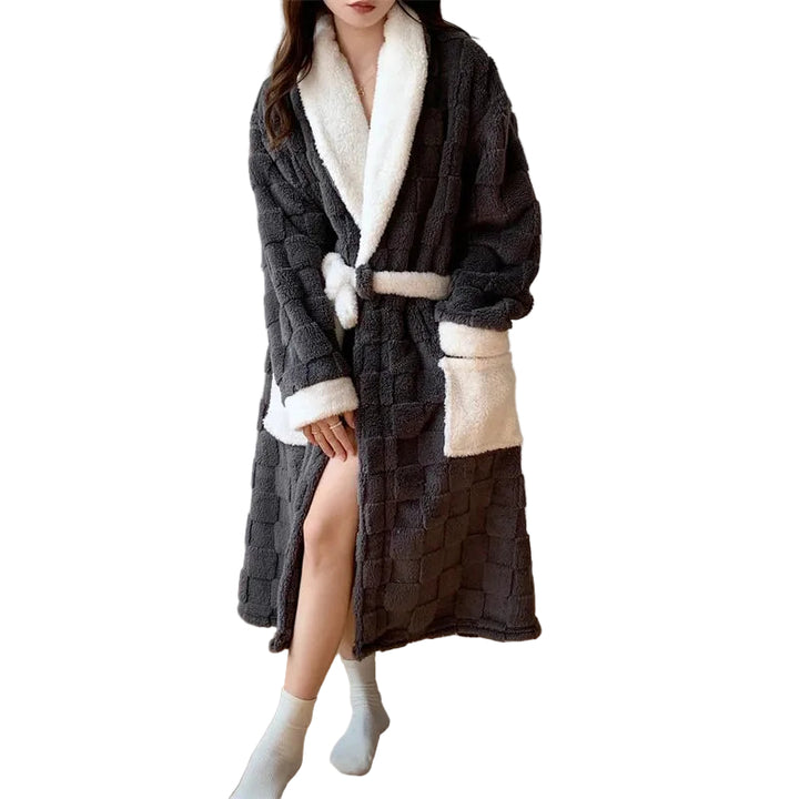Peignoir femme chaud et confortable  Fayette long en tissu peluche gris anthracite à effet matelassé, col châle, poignets et ceinture blancs, avec poches contrastées, porté en intérieur.