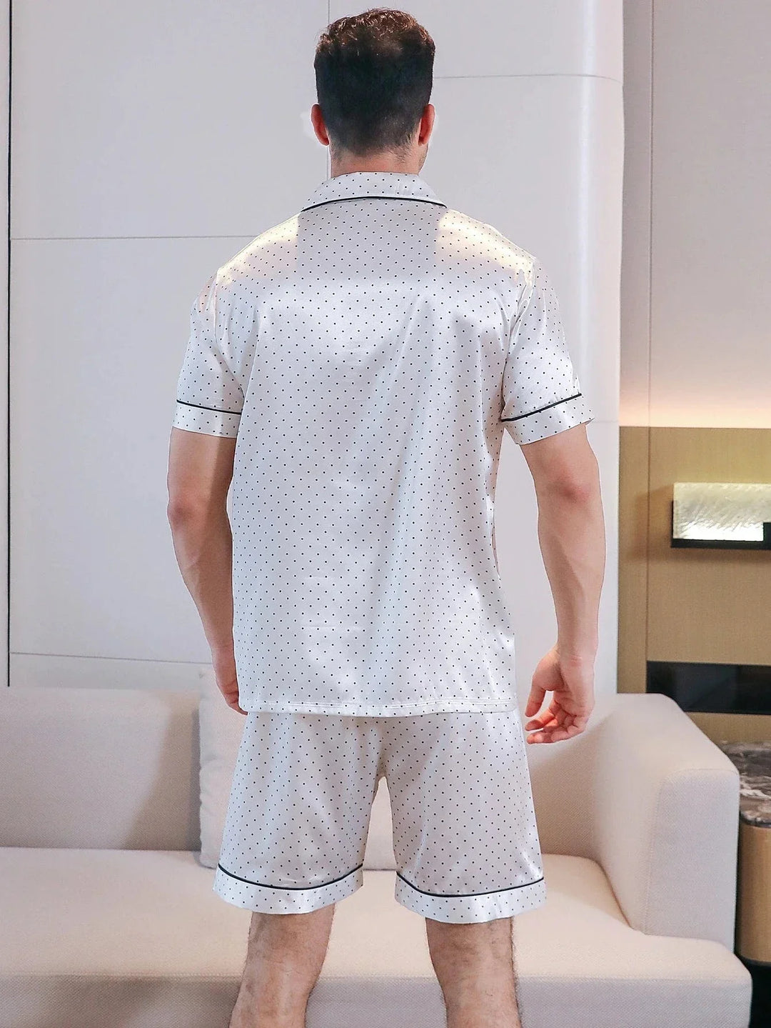 Vue de dos d’un homme portant le shorty satin pour homme Fernand, ensemble élégant et confortable composé d’une chemise à manches courtes et d’un short en satin clair à pois fins, avec finitions contrastées, offrant une coupe soignée et un tombé fluide idéal pour le confort à la maison.