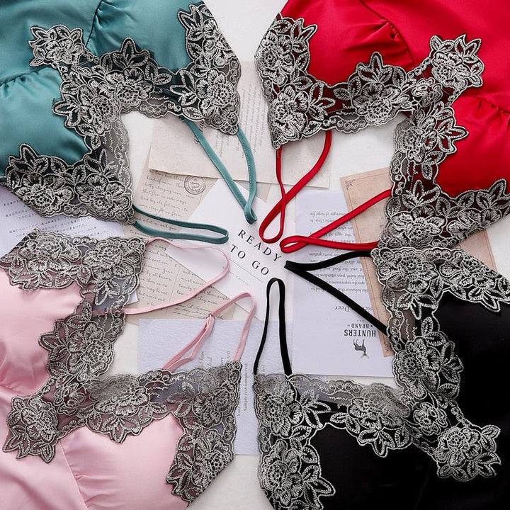 Vue rapprochée de plusieurs hauts de nuisette en satin aux couleurs variées (noir, rouge, rose, vert, bleu), ornés de fines dentelles florales grises. Détail raffiné illustrant l&