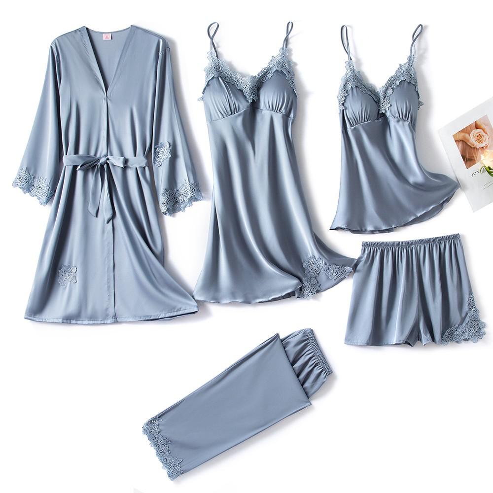 Ensemble de nuit pour femme en satin bleu pastel, composé de six pièces : un kimono ceinturé à manches longues, une nuisette à bretelles fines, un débardeur, un short, un pantalon long et une culotte (hors cadre). Chaque pièce est ornée de délicates finitions en dentelle ton sur ton. Parfait pour un sommeil confortable avec une touche d’élégance.