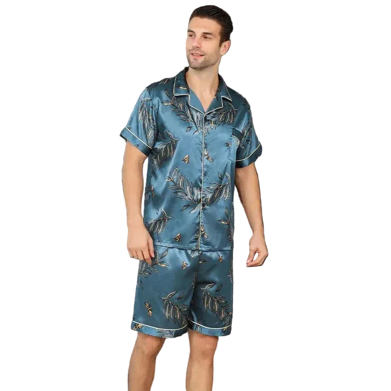 Homme debout portant le shorty satin François pour homme, ensemble deux pièces avec chemise boutonnée à manches courtes et short assorti, imprimé feuillage sur fond bleu-vert, coupe droite, présenté en intérieur.
