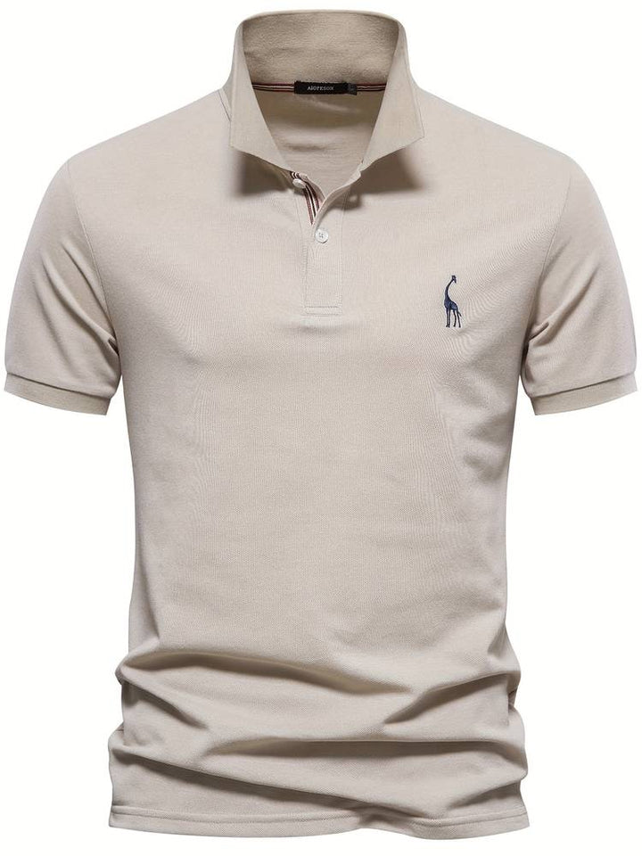 Ce polo slim pour homme, de couleur beige, combine confort et style. Il présente un col avec des détails rayés et un logo de girafe brodé sur la poitrine. Sa coupe ajustée et son design épuré en font un choix parfait pour un look moderne et élégant, adapté à toutes les occasions.