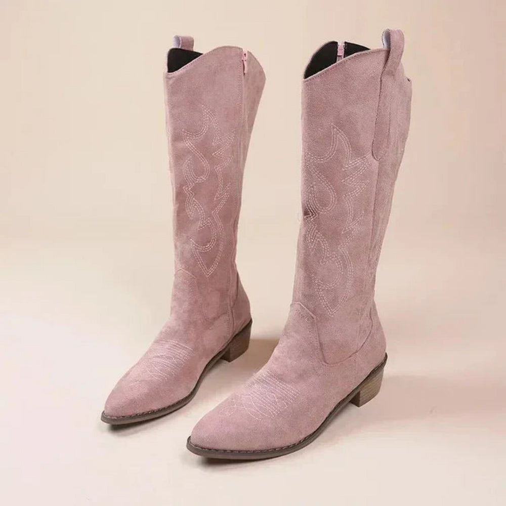Bottes western en suédine rose poudré, tige haute avec surpiqûres décoratives, bout légèrement pointu et talon bas, présentées en paire.