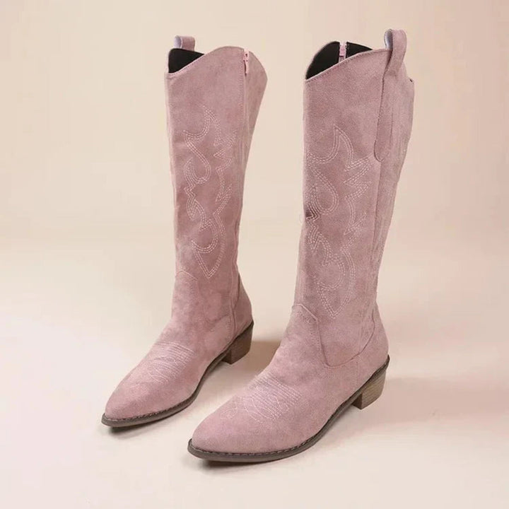 Bottes western en suédine rose poudré, tige haute avec surpiqûres décoratives, bout légèrement pointu et talon bas, présentées en paire.