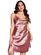 Femme portant une nuisette satinée rose ornée de motifs floraux dorés, avec fines bretelles et encolure drapée. Lingerie douce, féminine et élégante, idéale pour des nuits raffinées ou une allure glamour à la maison.