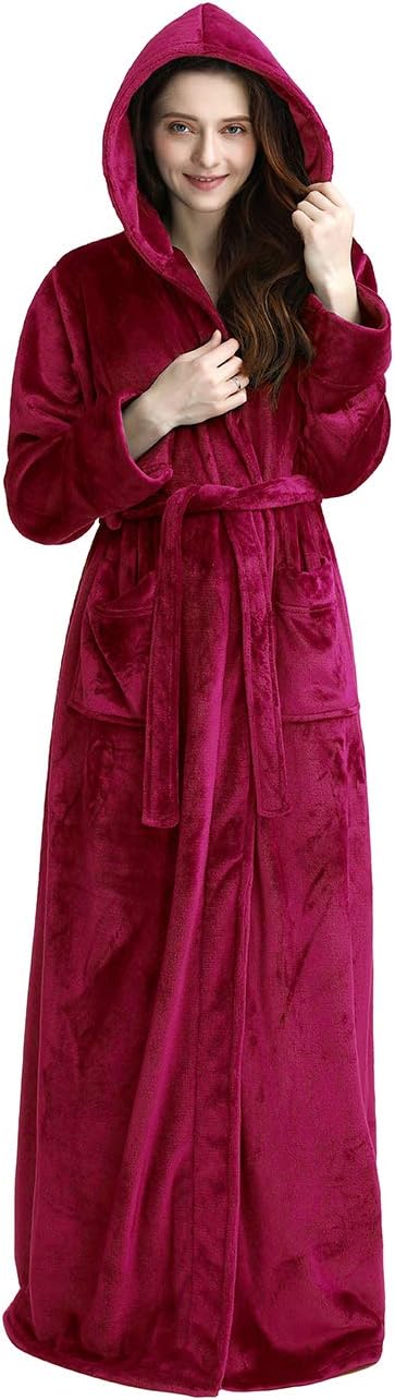 Femme souriante portant un peignoir à capuche en velours fuchsia, avec une ceinture et des poches, parfait pour se détendre avec style et confort.