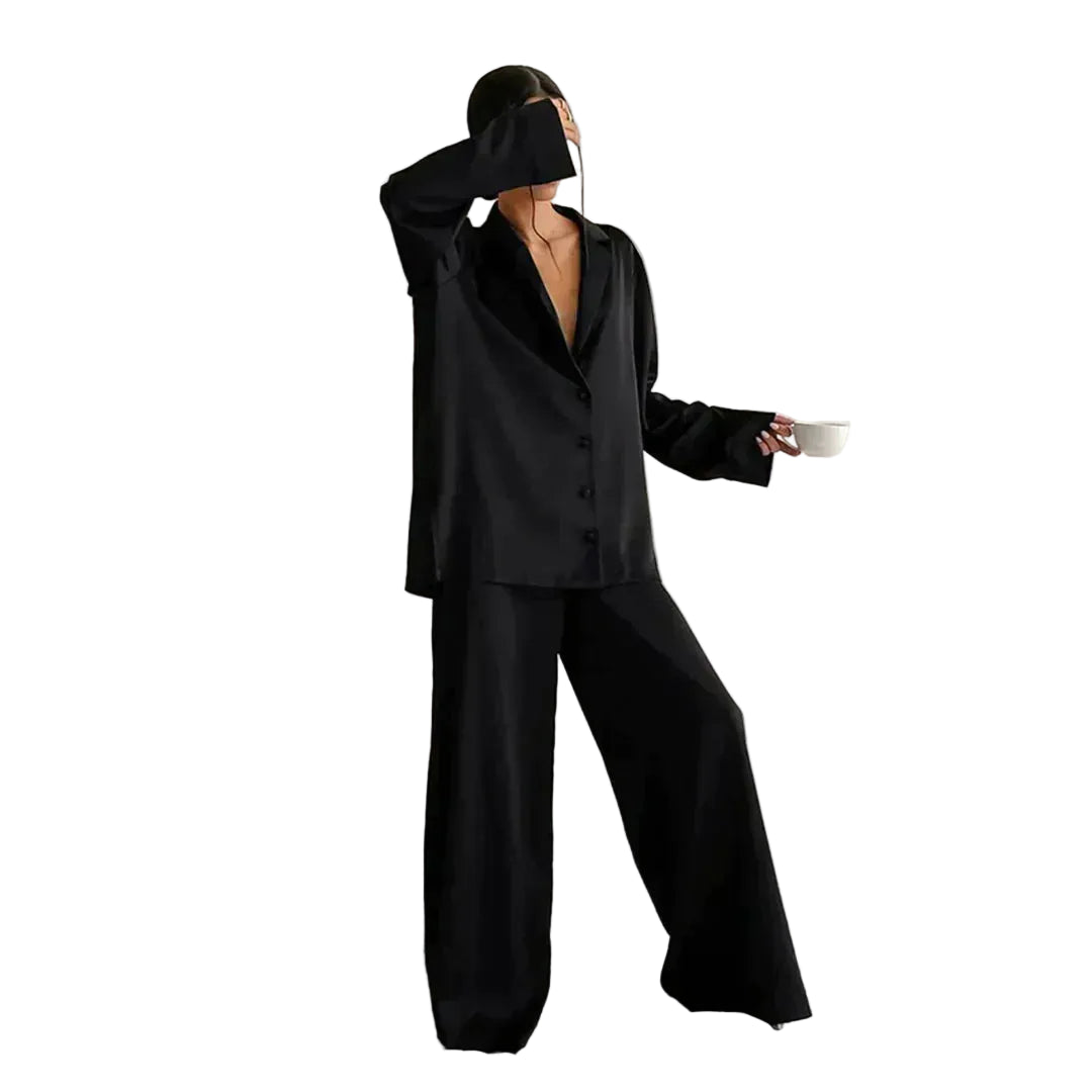 Femme portant le pyjama un ensemble noir élégant composé d’une chemise fluide à boutons et d’un pantalon large. Tenue douce et confortable, idéale pour la nuit et les moments de détente.