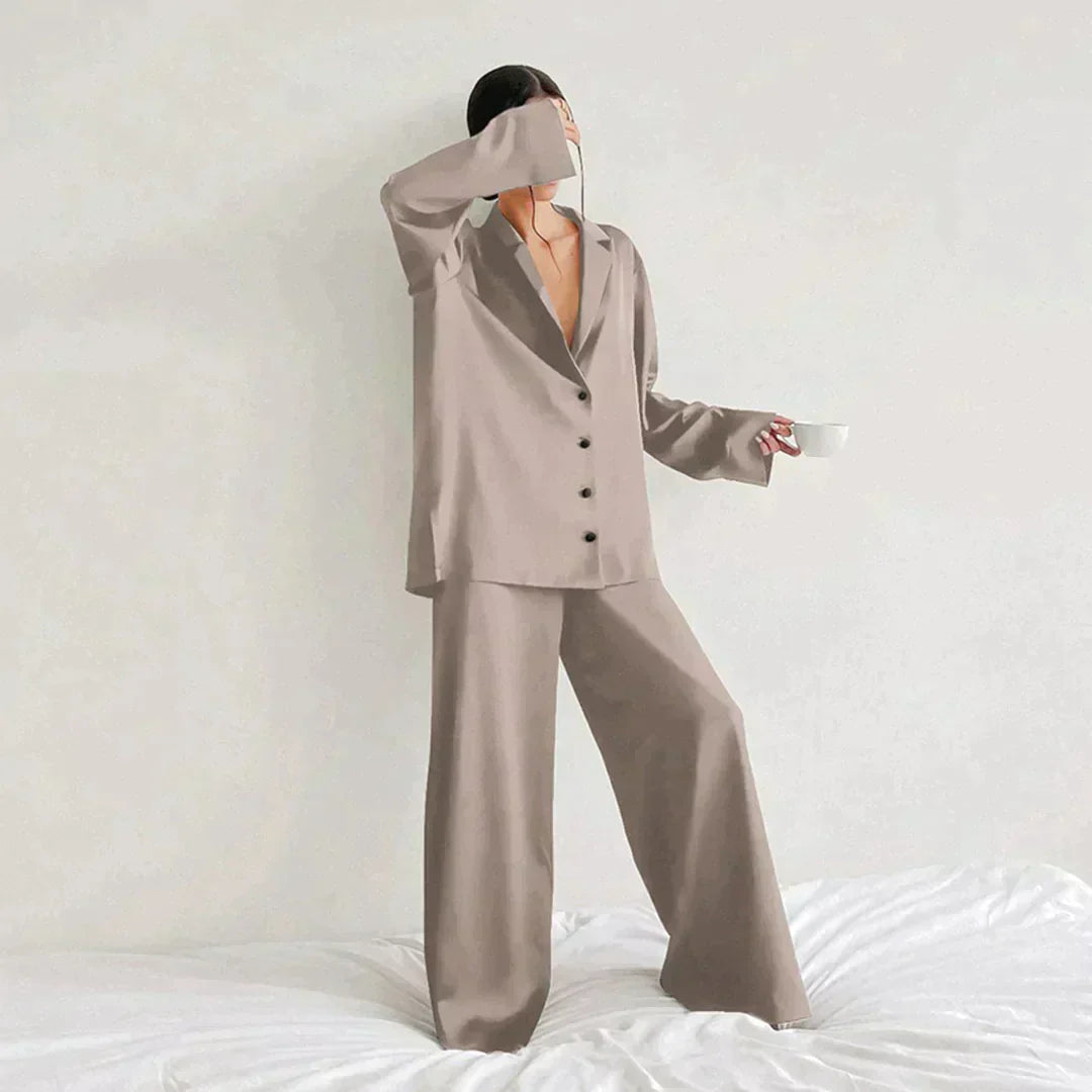Femme portant le pyjama en coloris beige, un ensemble élégant avec chemise fluide à boutons et pantalon ample. Tenue douce, chic et confortable, idéale pour la nuit et les moments de détente.