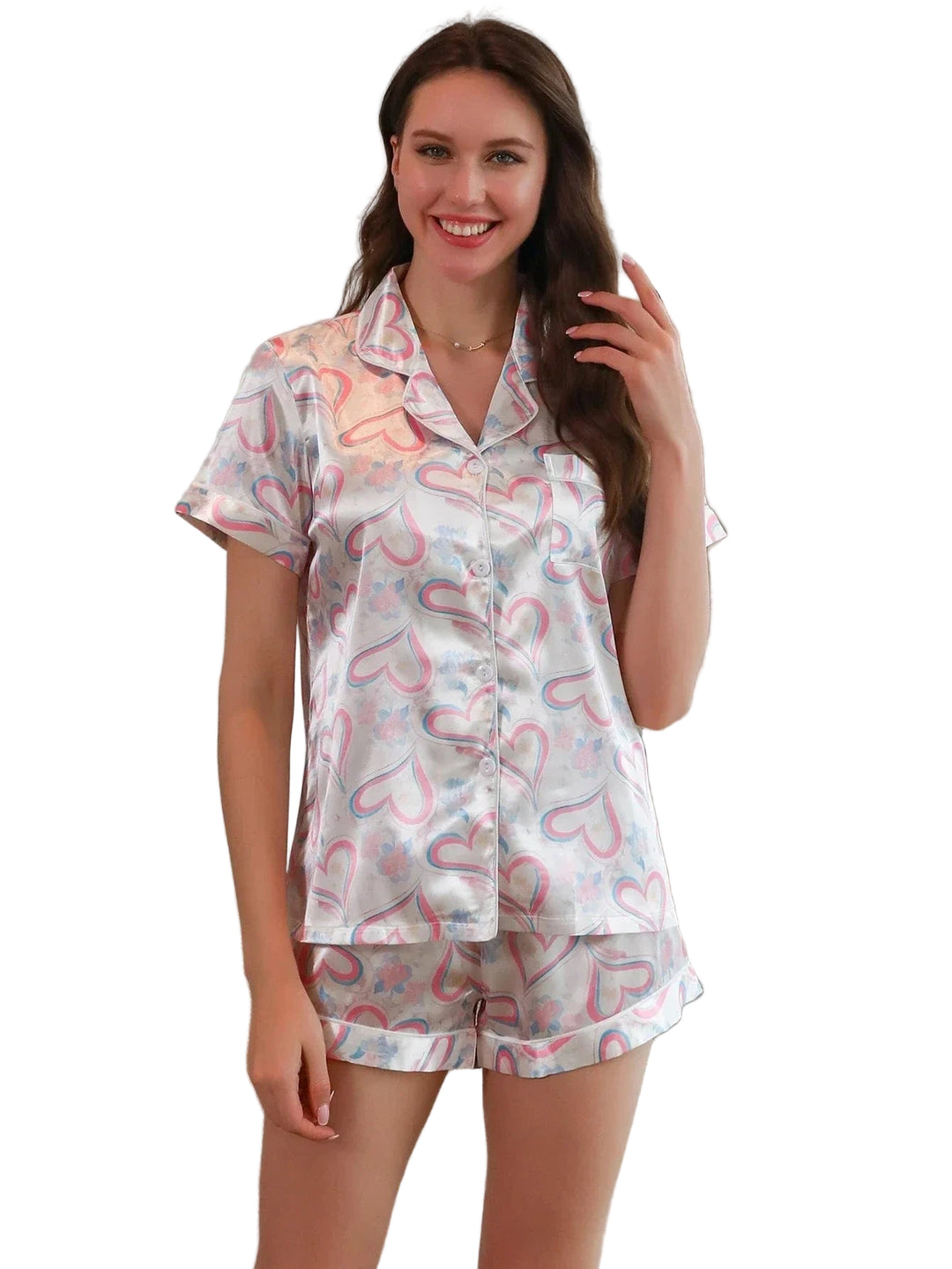 Femme portant le short de pyjama, un ensemble léger et confortable en satin blanc imprimé de cœurs roses et bleus, composé d’une chemise à manches courtes et d’un short assorti, photographiée dans un intérieur lumineux.