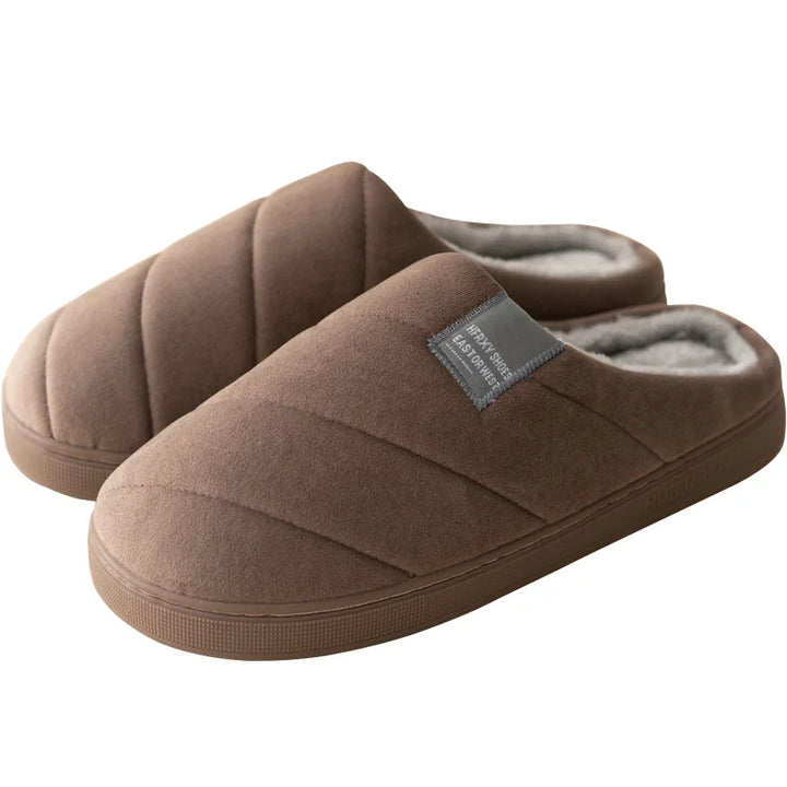 Chaussons unisexe Inaya marron, modèle matelassé avec étiquette grise, intérieur doublé en tissu doux et chaud, semelle épaisse antidérapante idéale pour la maison.