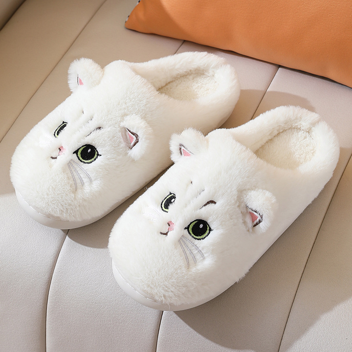 Chaussons femme Irene blancs, avec un design de tête de chat brodée, oreilles et yeux verts détaillés. Doublure en fourrure douce pour un confort chaleureux et tendance à la maison.