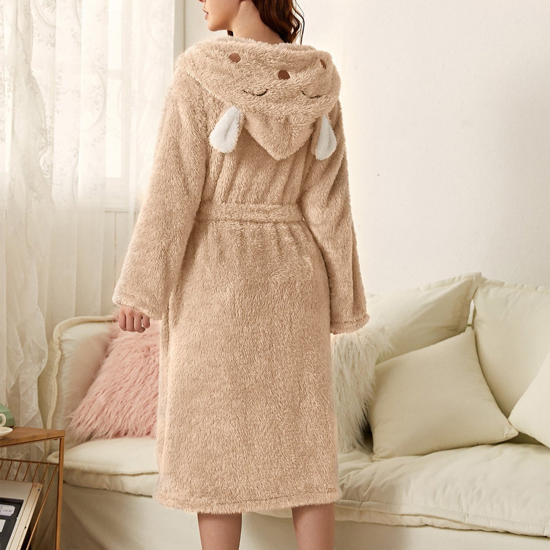 Peignoir femme chaud Iris en tissu peluche beige, coupe mi-longue avec ceinture, capuche fantaisie avec petites oreilles, porté de dos dans un salon.
