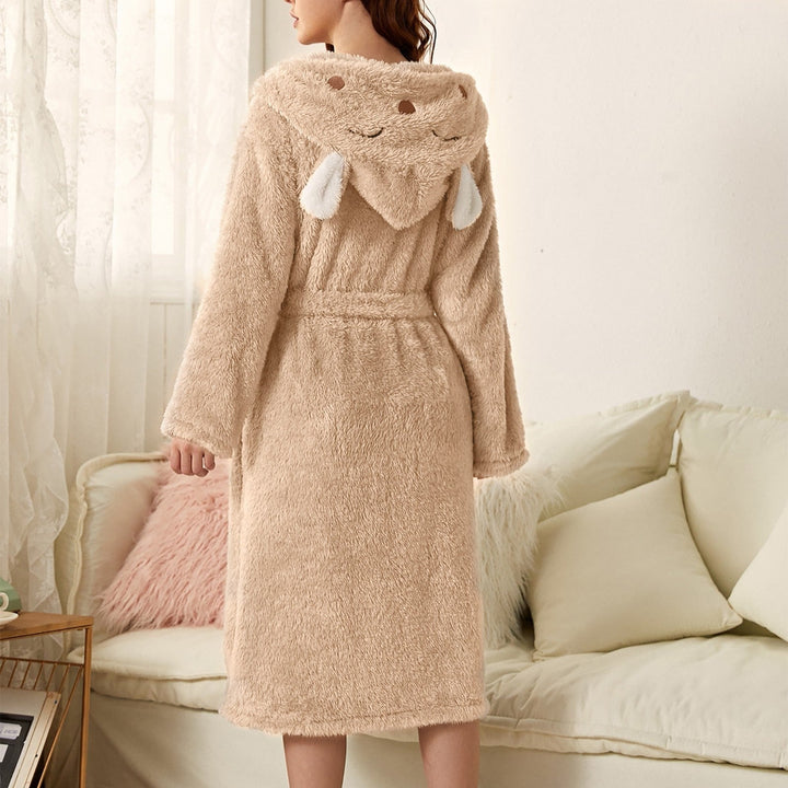 Peignoir femme chaud Iris en tissu peluche beige, coupe mi-longue avec ceinture, capuche fantaisie avec petites oreilles, porté de dos dans un salon.