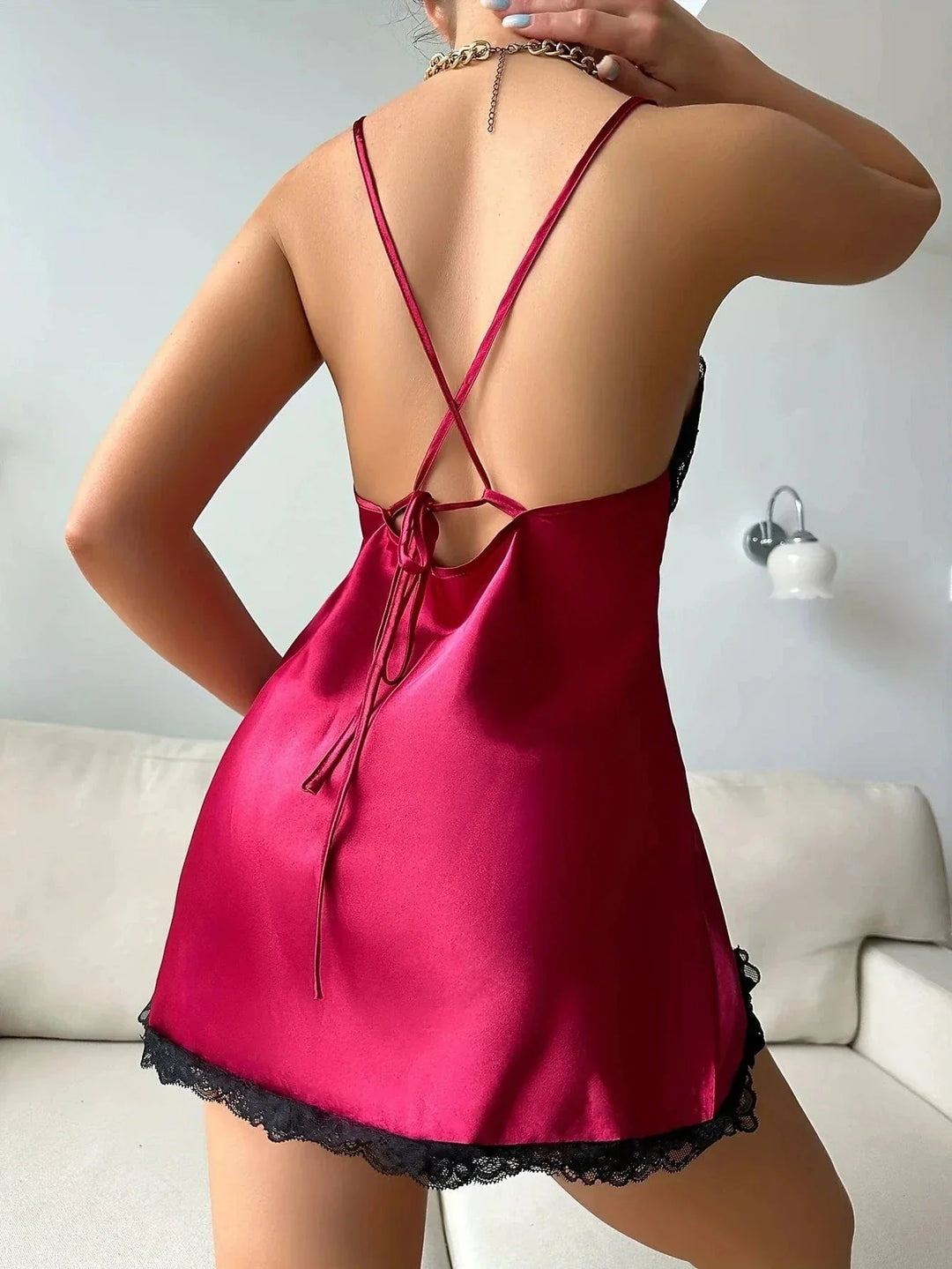 en satin rouge avec bretelles croisées et bordure en dentelle noire. Le tissu soyeux et la coupe sensuelle soulignent l’élégance nocturne du modèle.