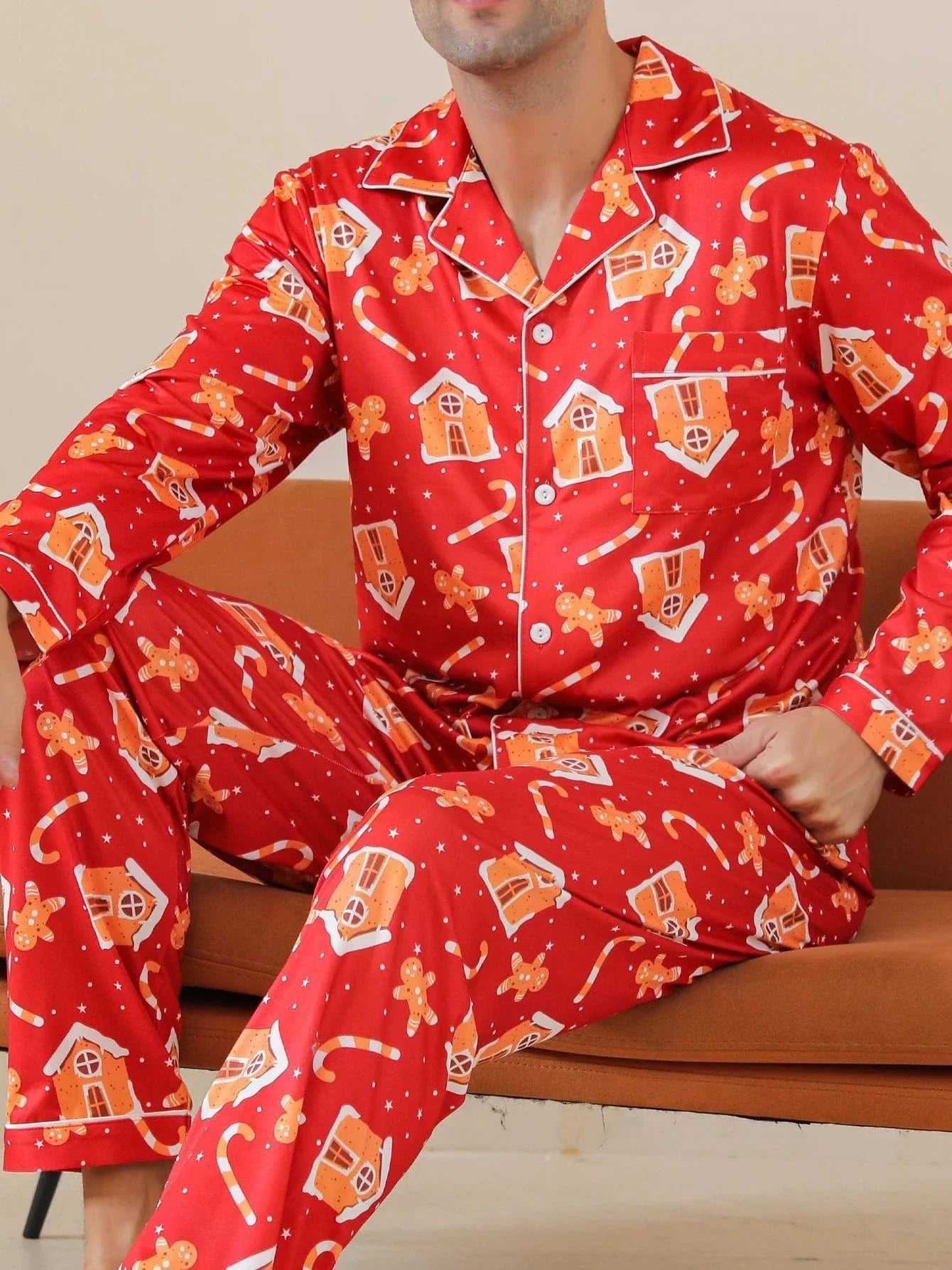 Vue rapprochée d’un homme portant le pyjama de Noël Jacques pour homme, ensemble deux pièces avec chemise boutonnée à manches longues et pantalon assorti, tissu rouge à motifs festifs de Noël, présenté en intérieur.