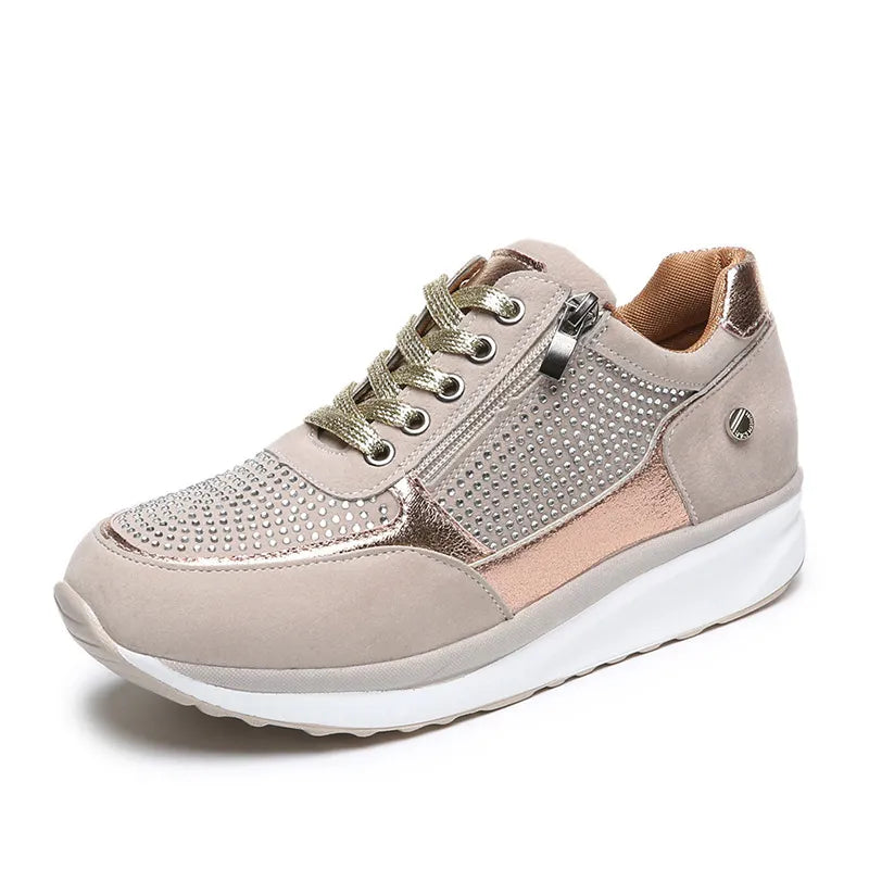 Baskets modernes pour femme, combinant cuir suédé beige et détails métalliques dorés. Avec des perforations élégantes et une fermeture éclair latérale pour un ajustement facile. Ces baskets sont parfaites pour un look tendance et un confort optimal tout au long de la journée.