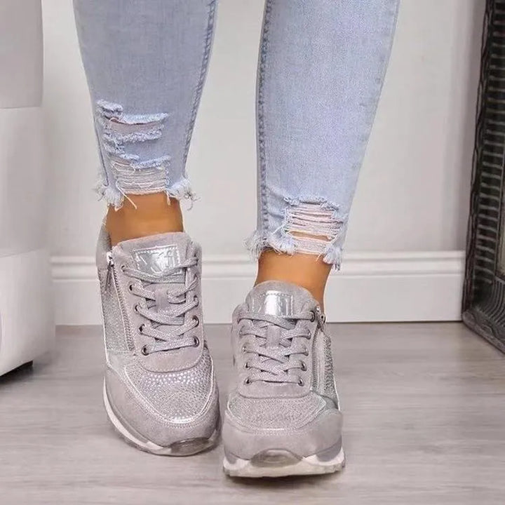 Baskets tendance pour femme en couleur argentée, avec des détails métalliques et une finition en cuir suédé. Le design perforé et la fermeture éclair latérale ajoutent une touche moderne. Ces baskets sont parfaites pour un style décontracté et élégant, tout en offrant un confort exceptionnel pour toute la journée.