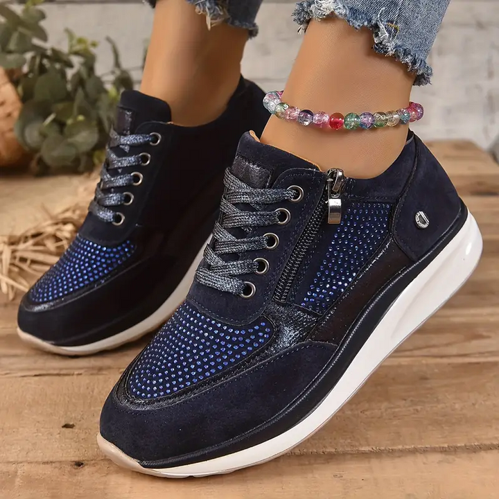 Baskets femme en bleu marine, avec des détails métalliques et un cuir suédé. Design perforé élégant, avec une fermeture éclair latérale et des lacets pour un ajustement parfait. Ces baskets sont idéales pour un look tendance et confortable, tout en offrant un excellent soutien grâce à leur semelle blanche épaisse.