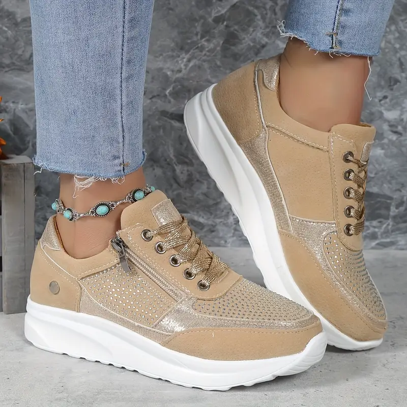 Baskets femme élégantes en beige avec des détails métalliques dorés et une finition en cuir suédé. Design perforé et fermeture éclair latérale pour un ajustement pratique. Ces baskets, avec leur semelle blanche et leur confort optimal, sont parfaites pour un look tendance et décontracté, tout en assurant un soutien tout au long de la journée.