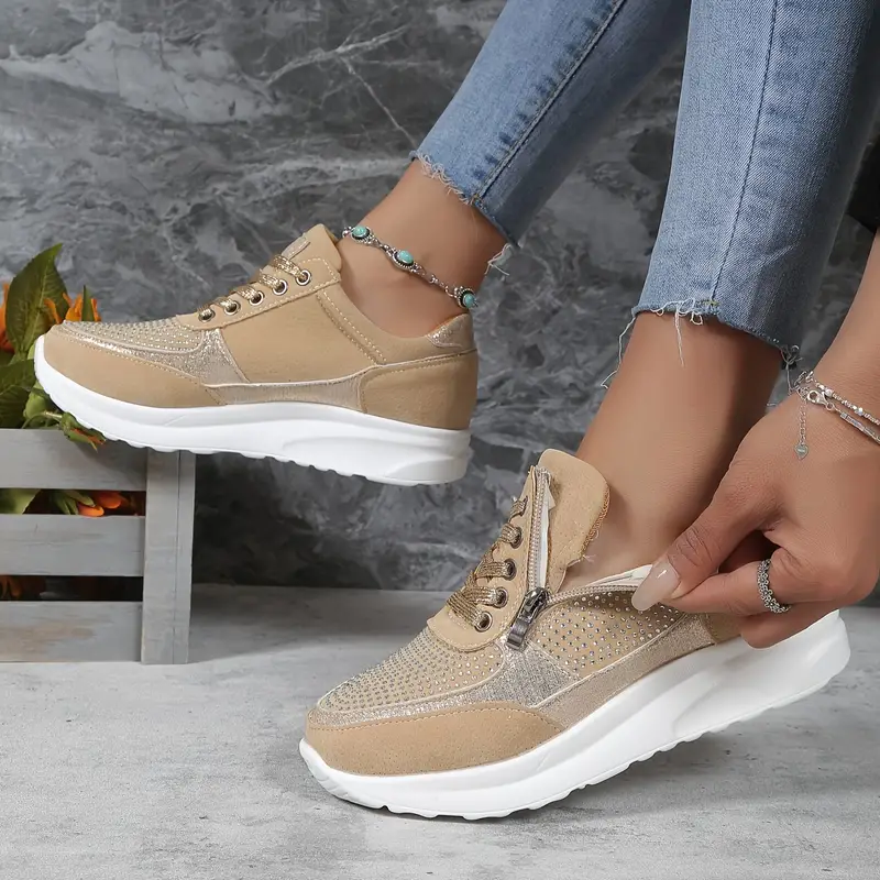 Baskets femme en beige, avec des détails métalliques dorés et un cuir suédé doux. Le design perforé et la fermeture éclair latérale permettent un ajustement facile et pratique. Ces baskets, dotées d&