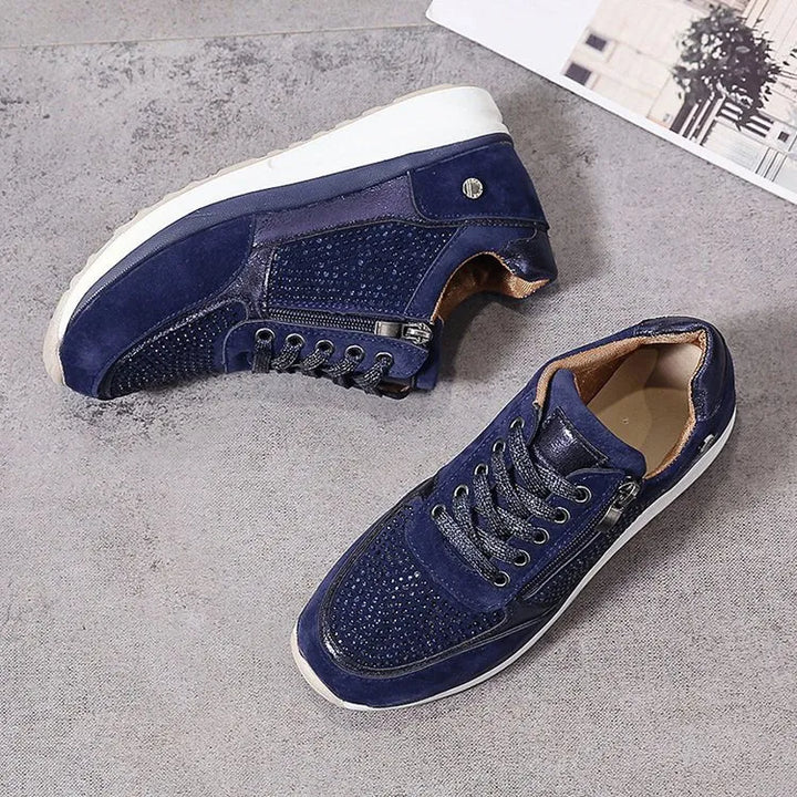 Baskets femme bleu marine, avec des détails perforés et une finition en cuir suédé. Le design élégant inclut une fermeture éclair latérale et des lacets pour un ajustement optimal. Ces baskets combinent confort et style moderne, avec une semelle blanche épaisse pour un soutien supplémentaire tout au long de la journée.