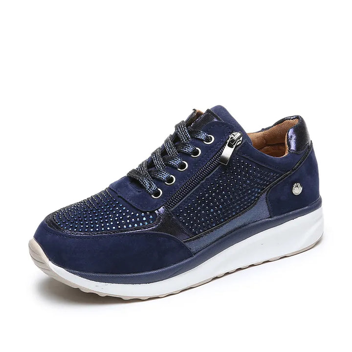 Baskets femme en bleu marine avec des détails métalliques brillants et une finition en cuir suédé. Design perforé élégant, fermeture éclair latérale et lacets pour un ajustement parfait. Parfaites pour un look à la fois moderne et confortable, ces baskets offrent un excellent soutien grâce à leur semelle blanche épaisse.