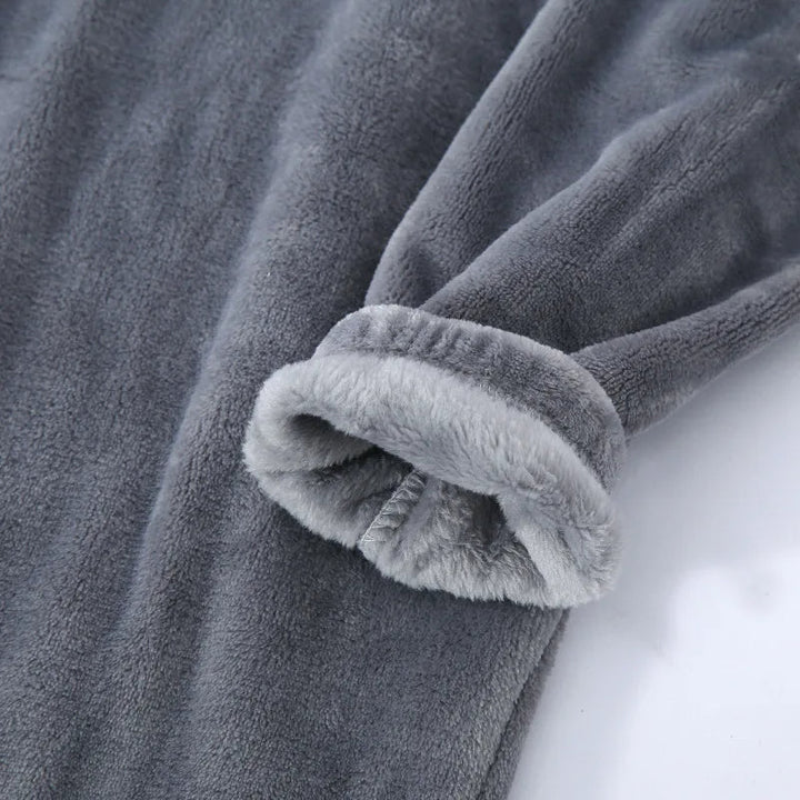Gros plan sur la manche d’un pyjama en flanelle pour homme, en tissu gris ultra doux et moelleux. Finition chaude, confortable et idéale pour l’hiver et les moments de détente.