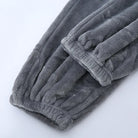 Gros plan sur le bas du pantalon d’un pyjama en flanelle pour homme, en tissu gris épais et ultra doux, avec chevilles élastiquées. Matière chaude, moelleuse et très confortable, idéale pour l’hiver.
